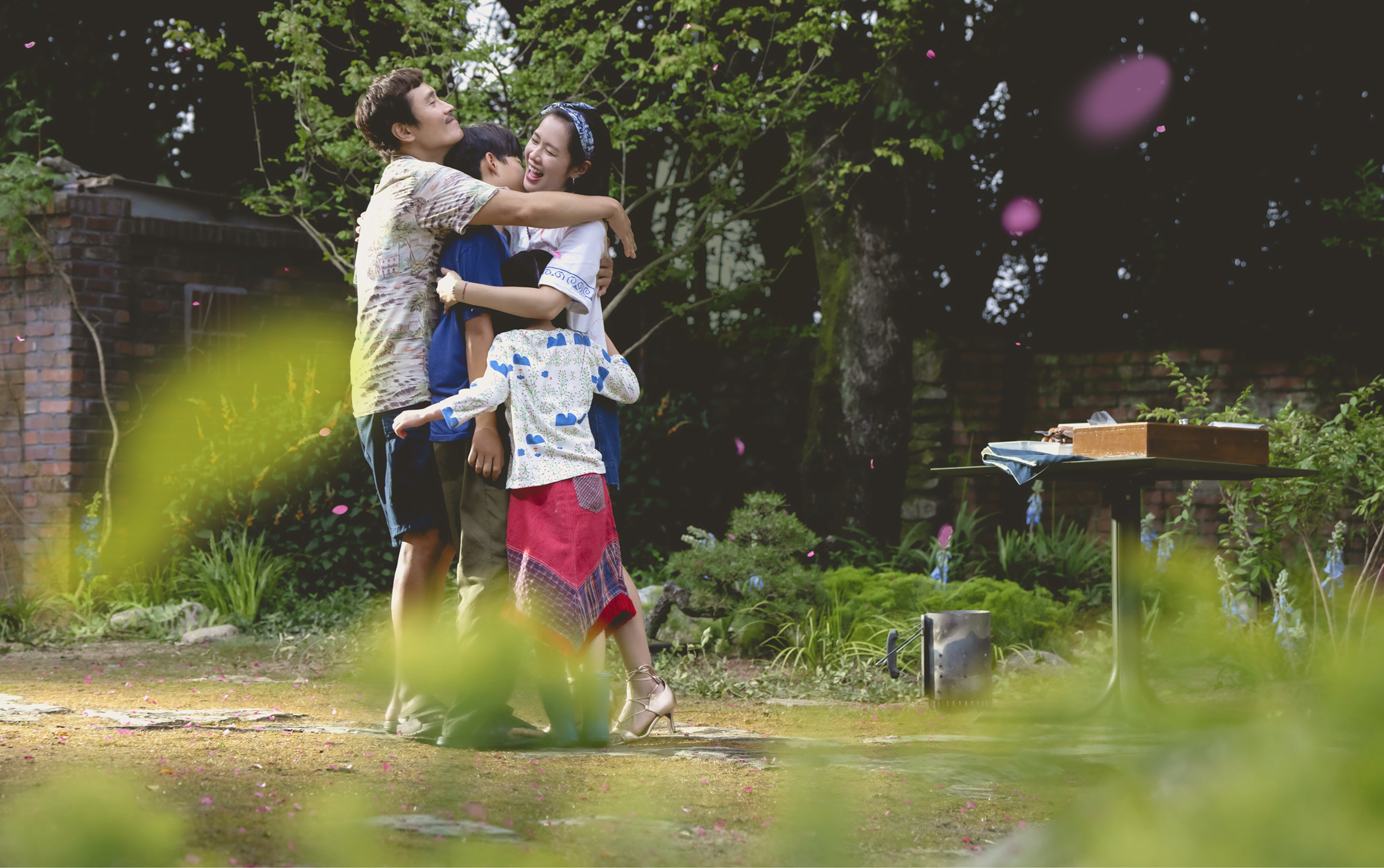 幸せそうな父と母、息子、娘が庭で抱き合っている